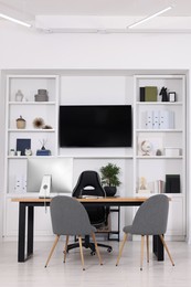 Photo of Stylish director's workplace with wooden table, tv zone and comfortable armchairs in office. Interior design
