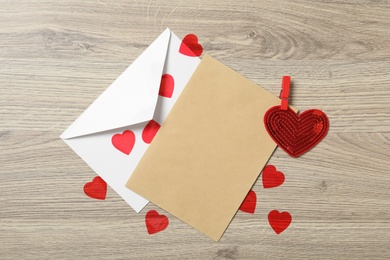 Photo of Blank card, envelope and hearts on wooden table, flat lay with space for text. Valentine's Day celebration