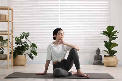 Beautiful girl sitting on yoga mat in studio