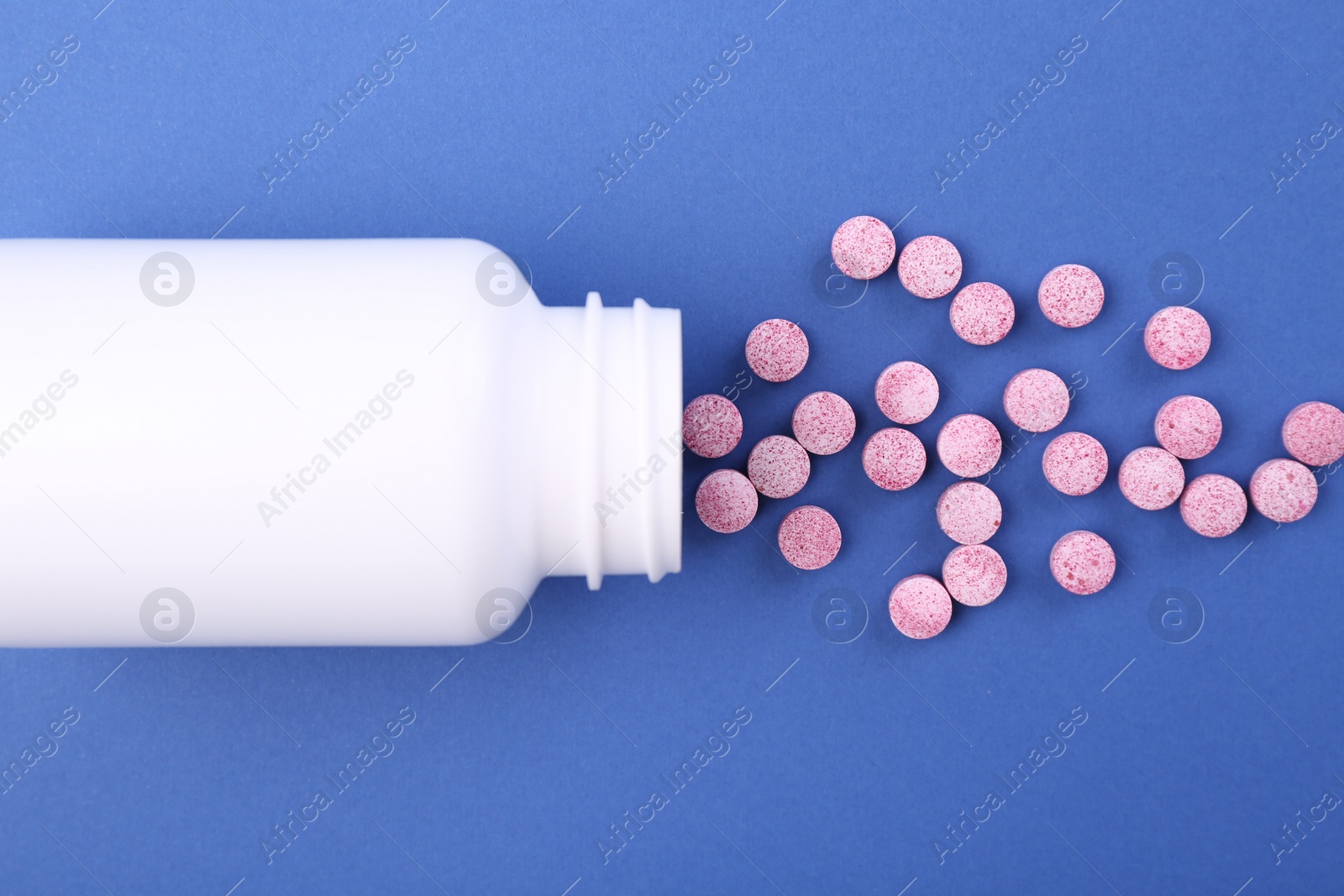 Photo of Bottle and vitamin pills on blue background, top view