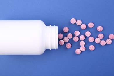 Photo of Bottle and vitamin pills on blue background, top view