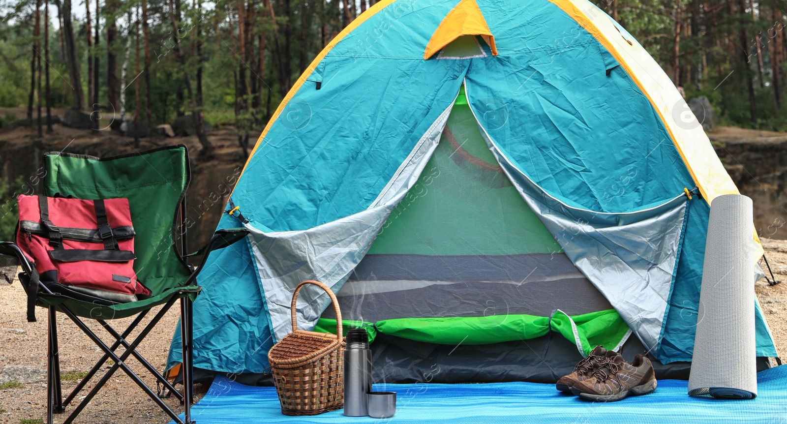 Image of Modern thermos, camping tent and other accessories outdoors