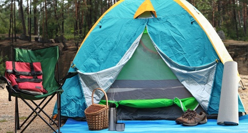 Image of Modern thermos, camping tent and other accessories outdoors