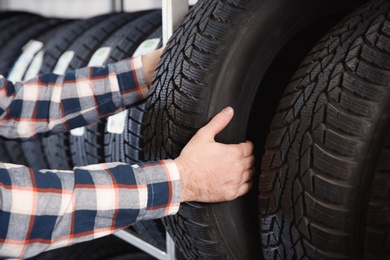 Photo of Male mechanic with car tires in automobile service center, closeup