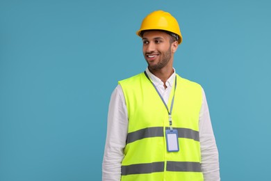 Photo of Engineer with hard hat and badge on light blue background, space for text
