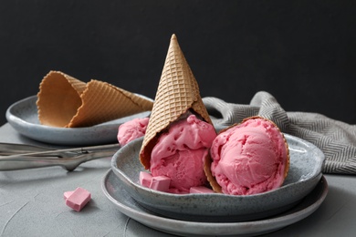 Photo of Delicious pink ice cream in wafer cones served on grey table