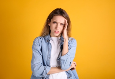 Portrait of stressed young woman on yellow background