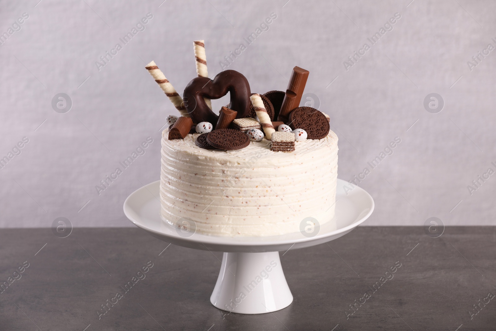 Photo of Delicious cake decorated with sweets on grey table