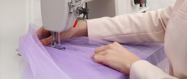 Dressmaker sewing new dress with machine in workshop, closeup. Banner design