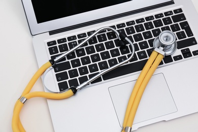 Photo of Modern laptop and stethoscope on table. Technical support concept