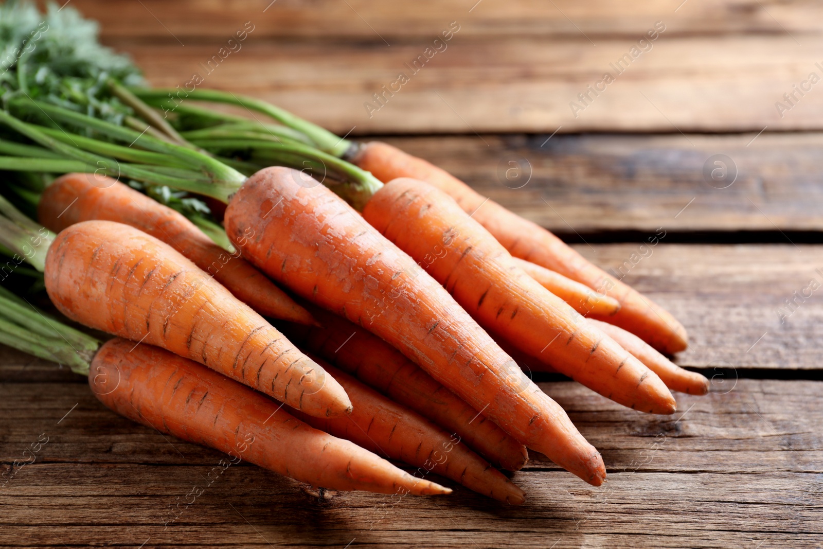 Photo of Fresh ripe carrots on wooden table, closeup