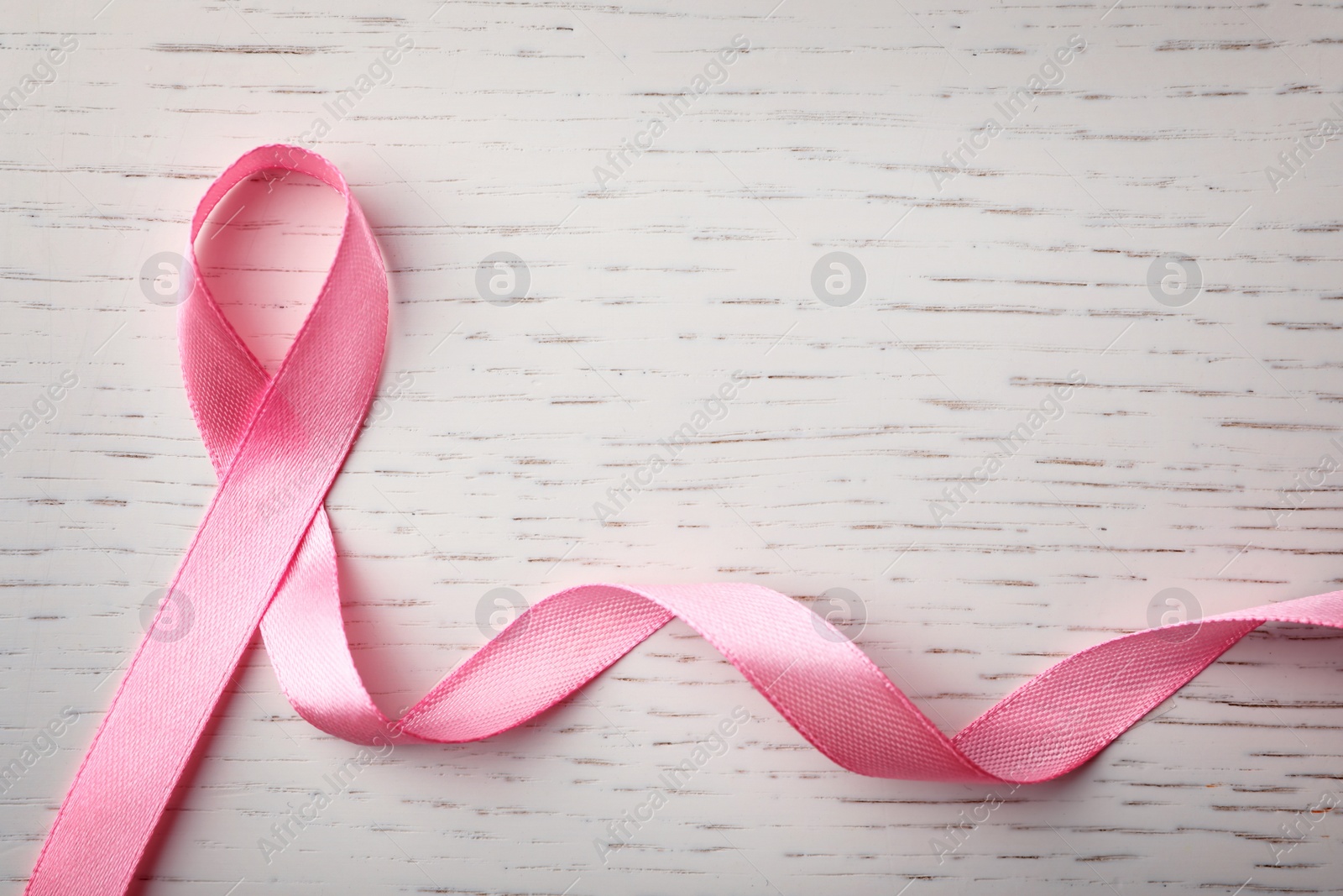 Photo of Pink ribbon on wooden background, top view with space for text. Breast cancer awareness concept