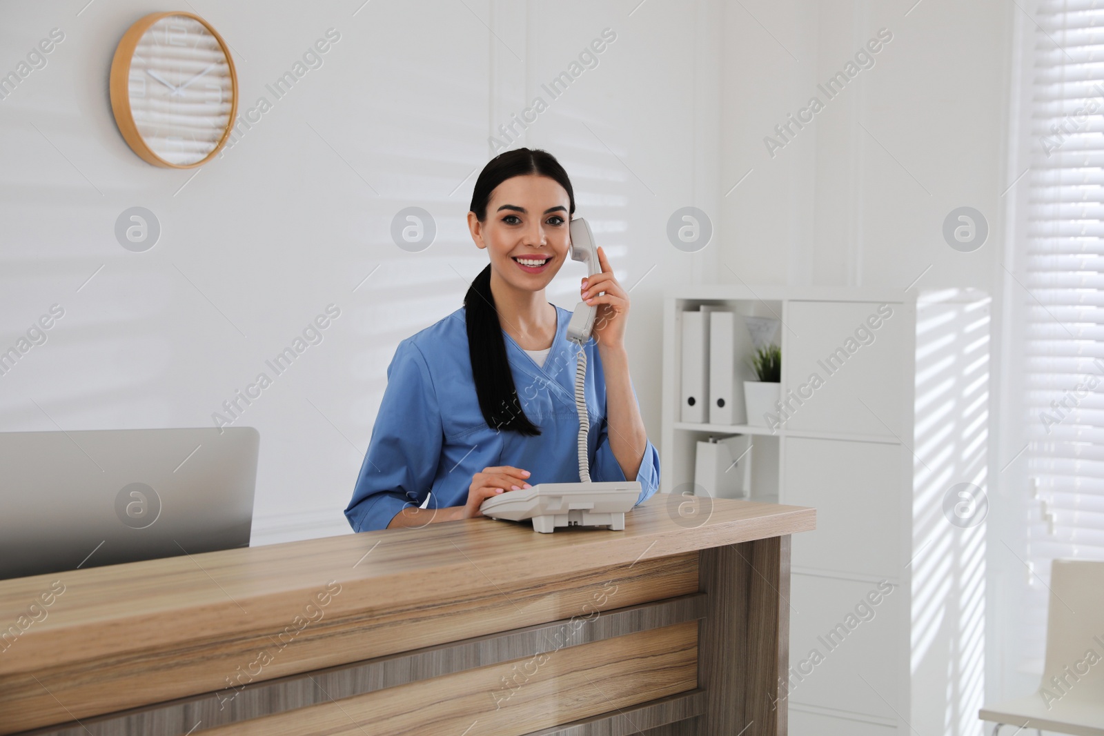 Photo of Receptionist talking on phone at countertop in hospital