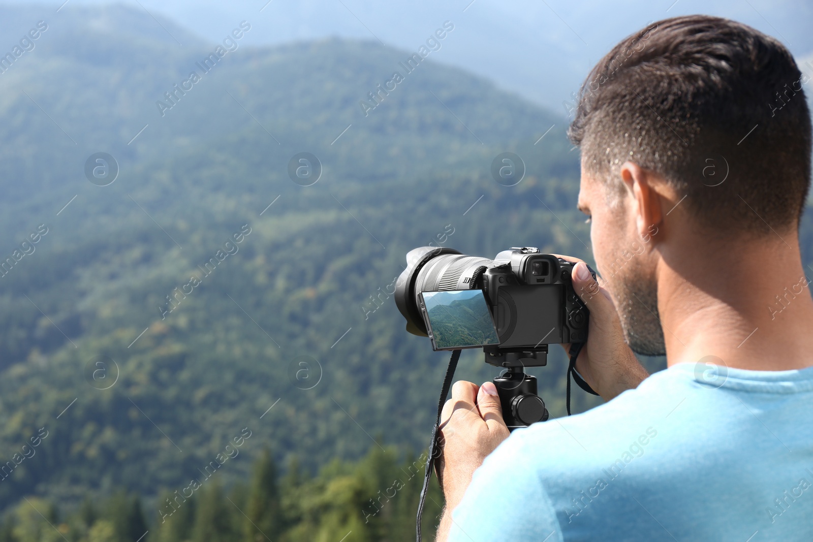 Photo of Man taking photo of nature with modern camera on stand outdoors