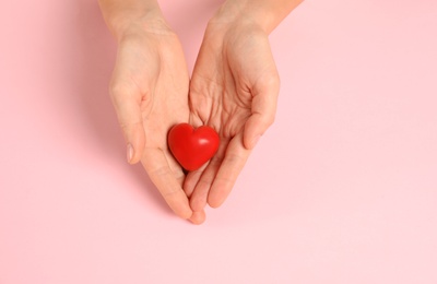 Photo of Woman holding decorative heart on color background, top view with space for text