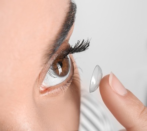 Photo of Young woman putting contact lens in her eye, closeup