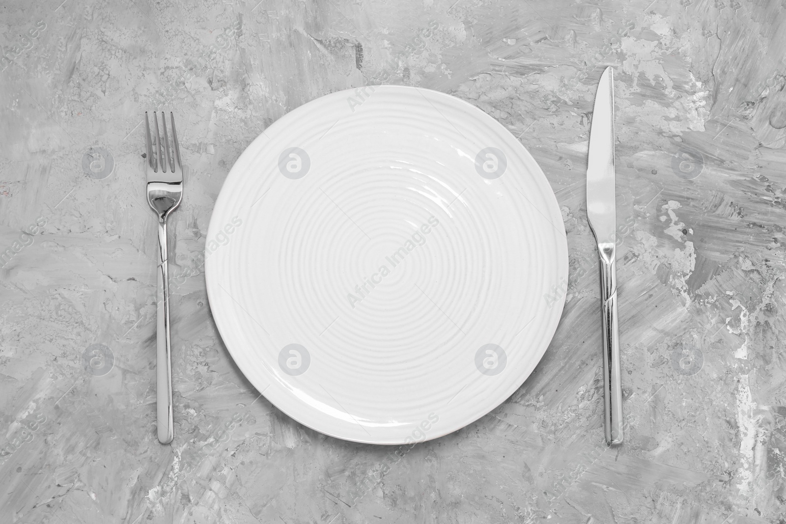 Photo of Elegant setting with shiny cutlery on grey table, top view