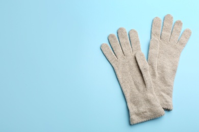 Pair of stylish woolen gloves on light blue background, flat lay. Space for text