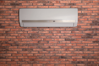 Image of Modern air conditioner on brick wall indoors