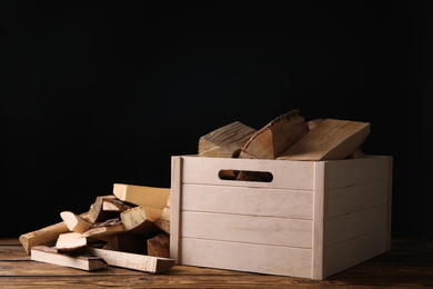 Photo of Cut firewood on table against black background