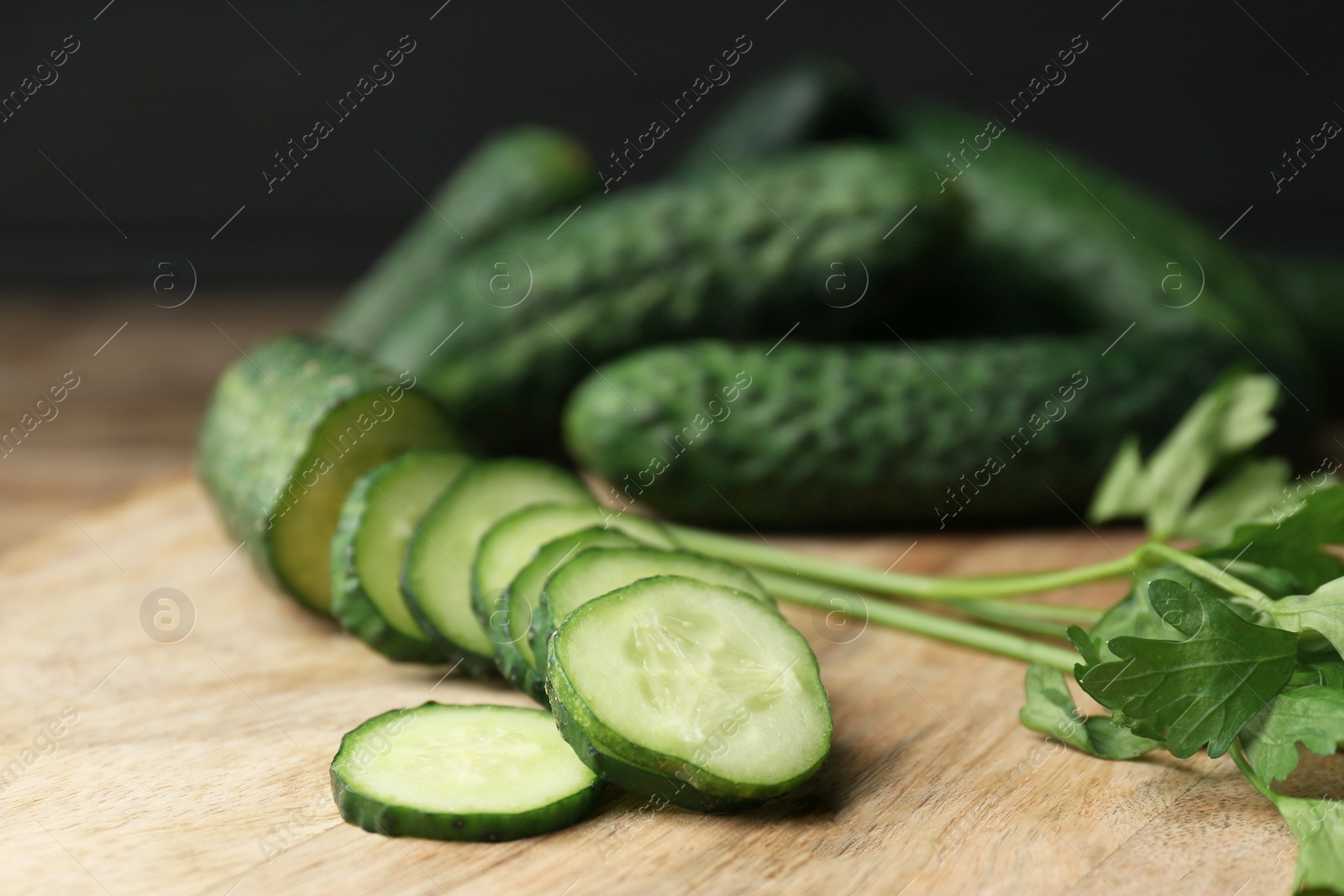 Photo of Fresh ripe cucumbers and parsley on wooden table, closeup