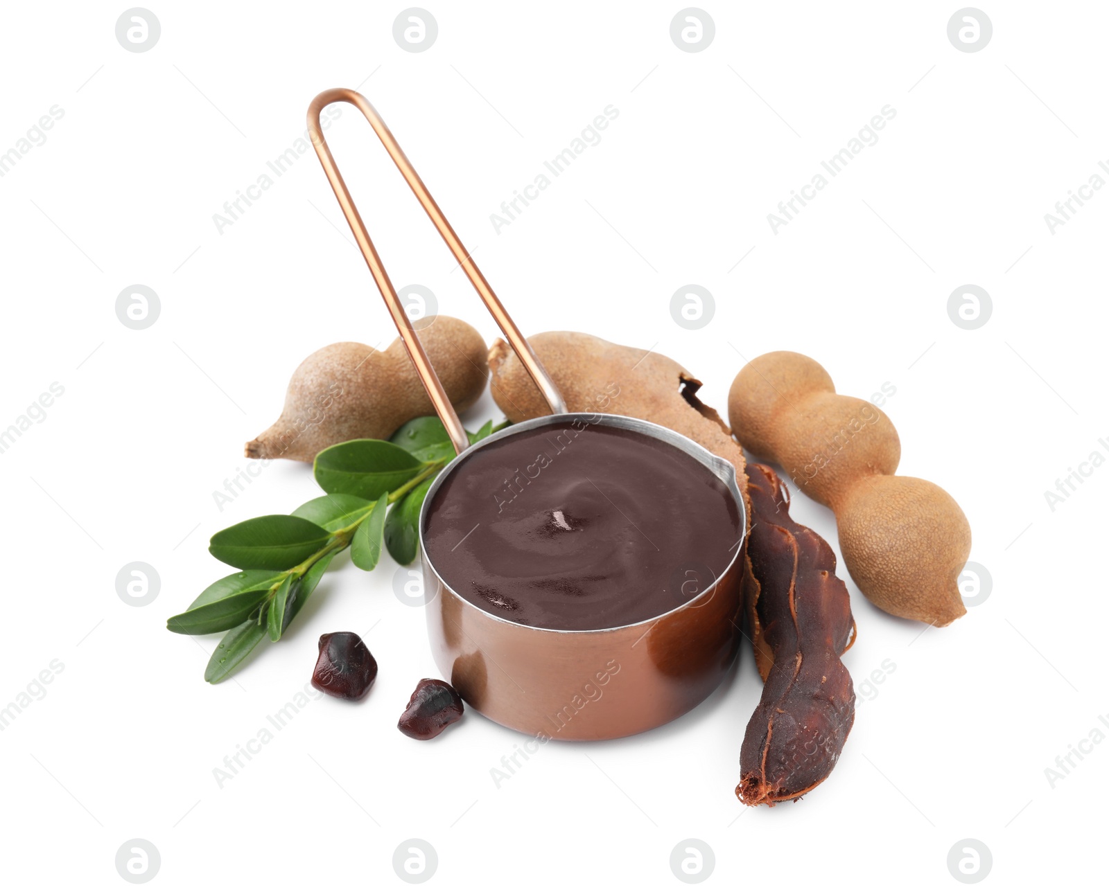 Measuring cup with tasty tamarind sauce, leaves and fresh pods isolated on white Photo of Measuring cup with tasty tamarind sauce, leaves and fresh pods isolated on white