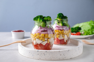 Photo of Healthy salad in glass jars on light table