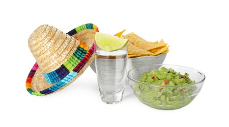 Photo of Mexican sombrero hat, tequila with lime, nachos chips and guacamole in bowls isolated on white
