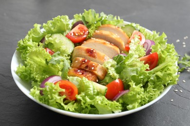 Photo of Delicious salad with chicken and vegetables on black table, closeup