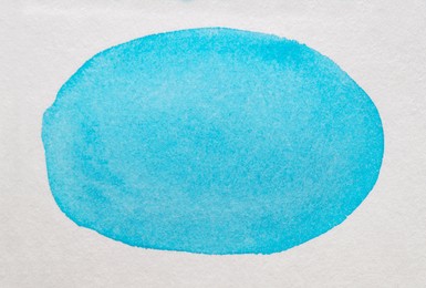 Photo of Oval made of light blue watercolor paint on white canvas, top view