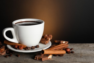 Photo of Cup of delicious hot chocolate, spices and coffee beans on wooden table. Space for text