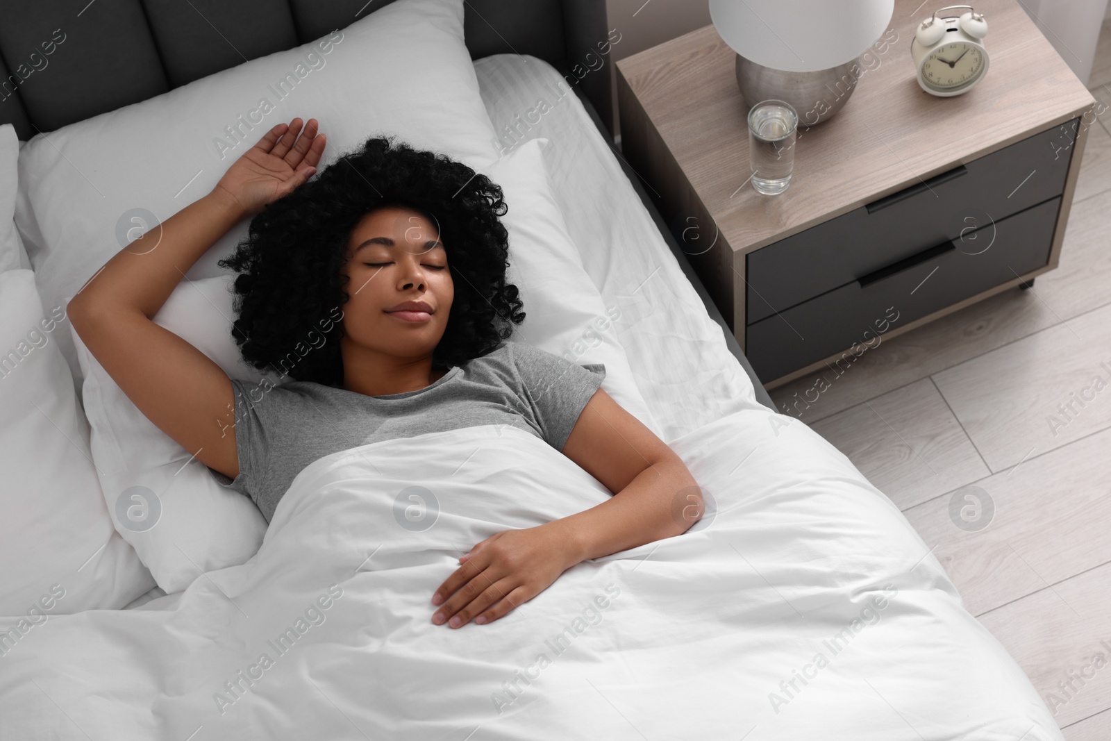 Photo of Beautiful young woman sleeping in soft bed at home, above view