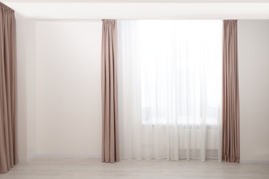 Photo of Elegant window curtains and white tulle indoors. Interior design