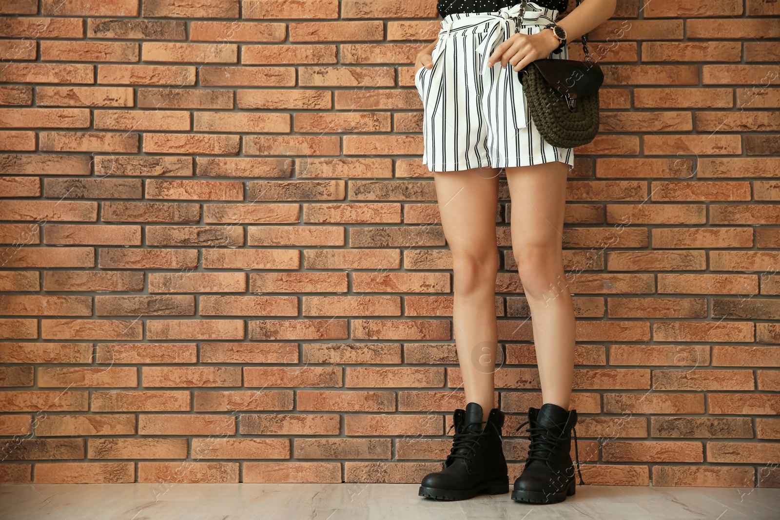 Photo of Young woman with sexy legs near brick wall