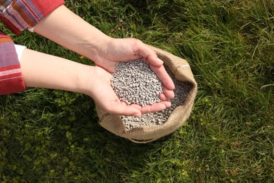 Photo of Woman with fertilizer on green grass outdoors, top view