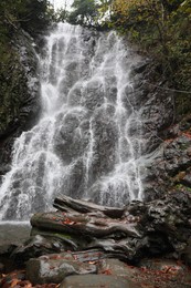 Picturesque view of beautiful mountain waterfall and rocks outdoors