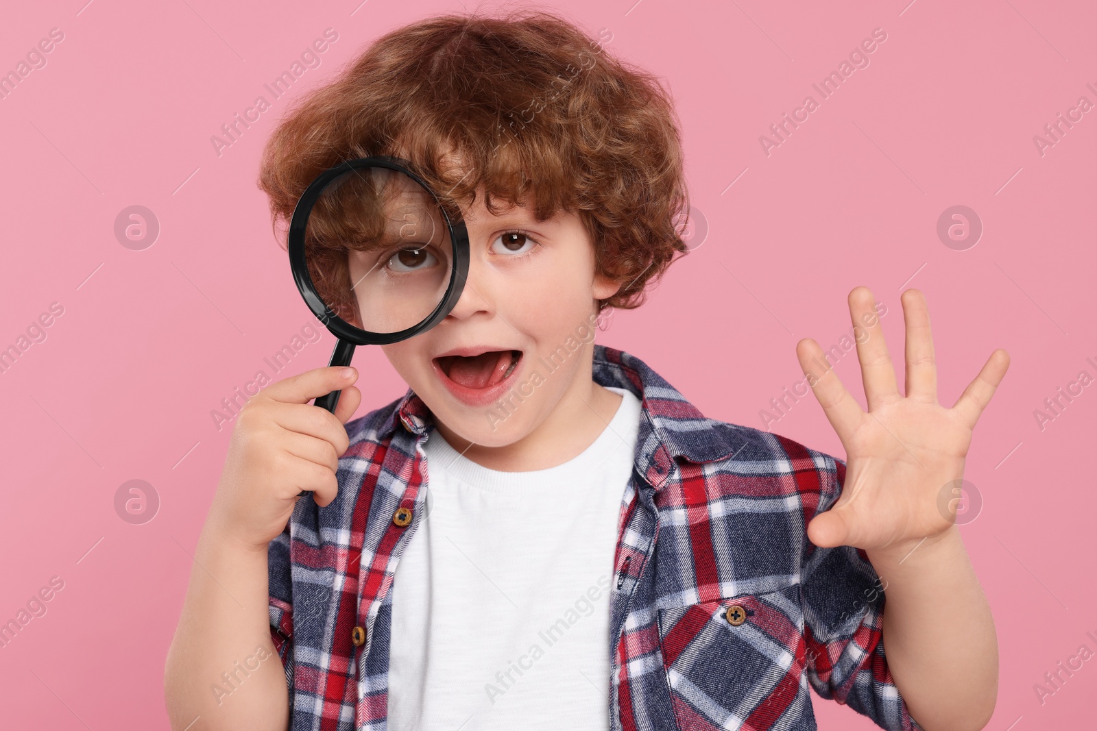 Photo of Cute little boy looking through magnifier glass on pink background