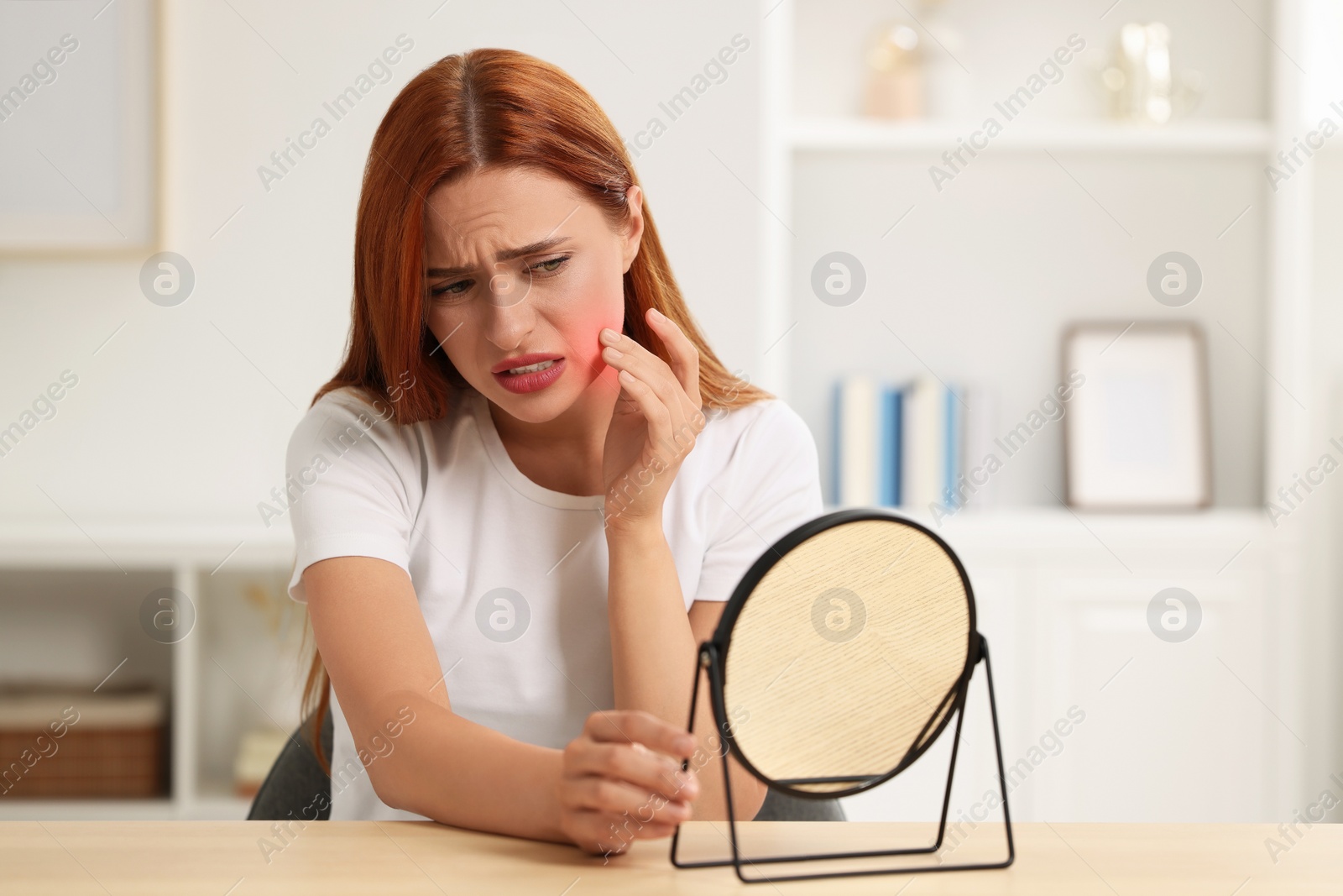 Photo of Suffering from allergy. Young woman with mirror checking her face at home