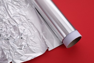 One roll of aluminum foil on red background, closeup