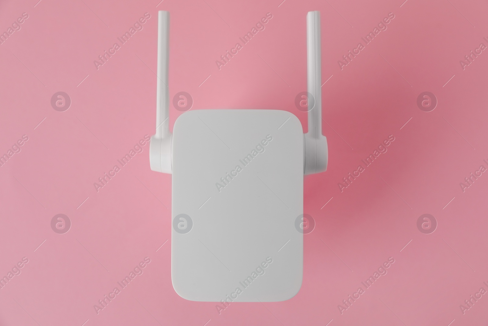 Photo of New modern Wi-Fi repeater on pink background, top view