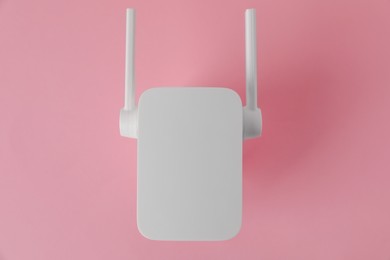 New modern Wi-Fi repeater on pink background, top view