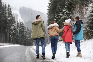 Group of friends walking near snowy forest. Winter vacation