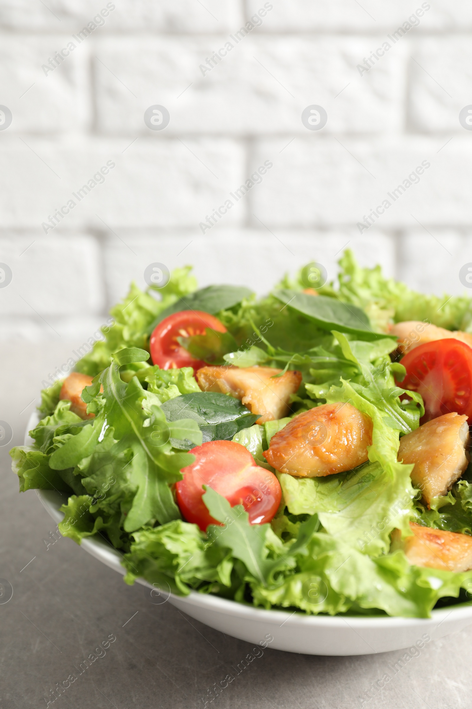 Photo of Delicious salad with chicken and cherry tomato on light grey table, closeup