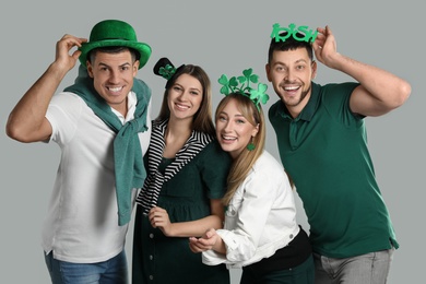 Happy people in St Patrick's Day outfits on light grey background