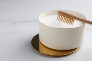 Bamboo toothbrush and bowl of baking soda on white marble table, closeup. Space for text