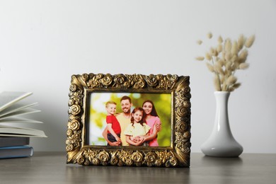 Photo of Vintage square frame with family photo, books and vase of dry flowers on wooden table
