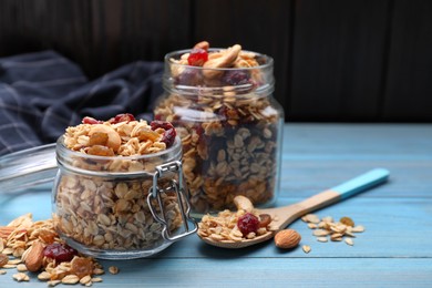 Jars of tasty granola with nuts and dry fruits on light blue wooden table. Space for text