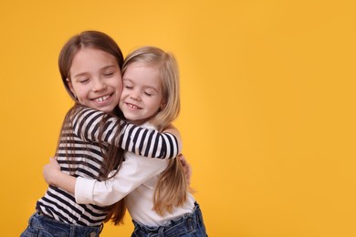 Photo of Portrait of cute little sisters on orange background, space for text