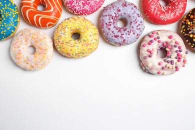 Photo of Delicious glazed donuts on white background, flat lay. Space for text