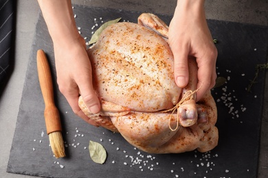 Photo of Woman preparing whole turkey at table, top view